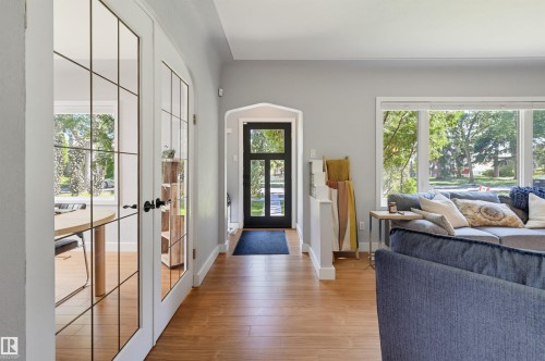 Wood-finish flooring throughout, framed glass double doors, a prominent front entry door, and large picture windows - 10726 128 Street Nw, Edmonton, AB 