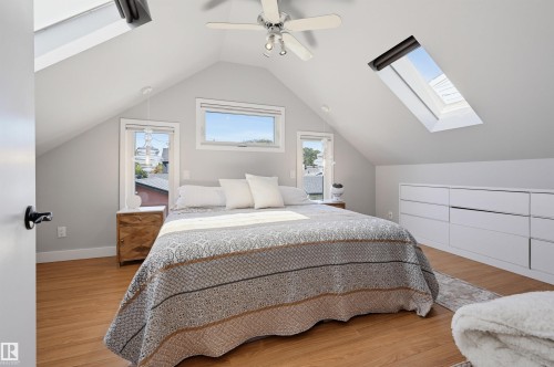 Vaulted ceilings featuring two skylights, a ceiling fan, wood-finish flooring, and built-in white cabinetry with ample storage - 10726 128 Street Nw, Edmonton, AB 
