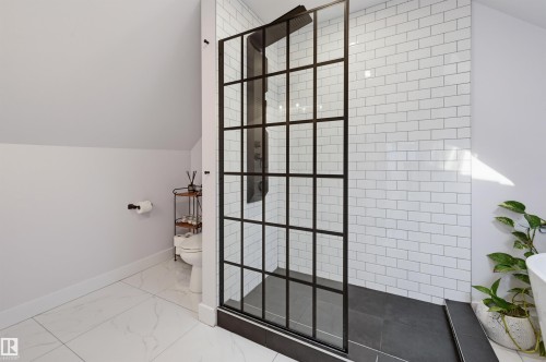 Walk-in shower with black-framed glass enclosure, white subway tile surround, and dark-toned shower floor - 10726 128 Street Nw, Edmonton, AB 
