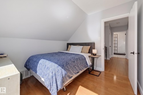 Hardwood flooring throughout, sloped ceiling detail, and a white interior door with black hardware - 10726 128 Street Nw, Edmonton, AB 