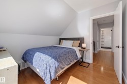 Hardwood flooring throughout, sloped ceiling detail, and a white interior door with black hardware - 