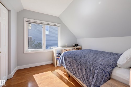Sloped ceiling room featuring wood-finish flooring, a double window, and a white bi-fold closet door - 10726 128 Street Nw, Edmonton, AB 