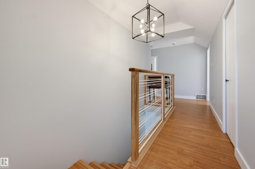 Hardwood flooring, contemporary chandelier, vaulted ceiling, wood and cable railing, and white interior doors - 10726 128 Street Nw, Edmonton, AB 