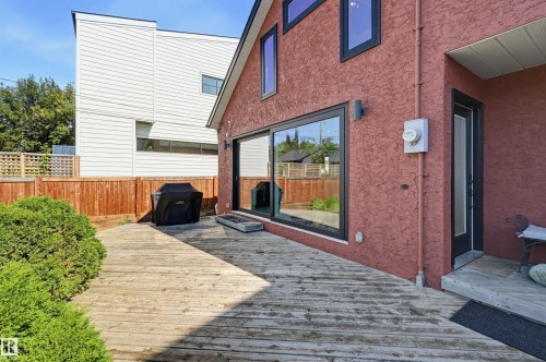 Expansive wood-plank deck with a privacy fence, a stucco exterior, and a large sliding glass door - 10726 128 Street Nw, Edmonton, AB 