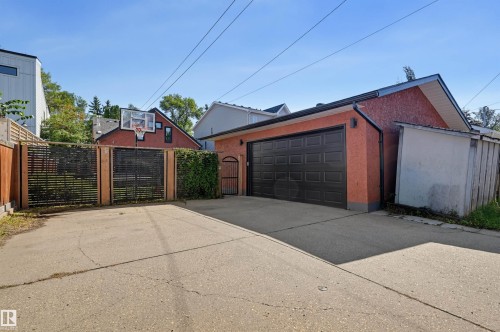 Detached garage with a black panel door, a side entry gate, and an attached storage shed - 10726 128 Street Nw, Edmonton, AB 