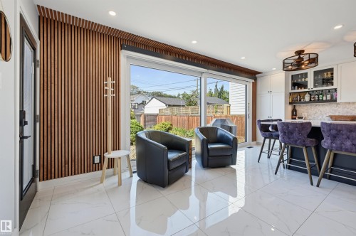 Wood-slat accent wall, white tile flooring, sliding glass door, built-in bar cabinetry, and recessed lighting - 10726 128 Street Nw, Edmonton, AB 