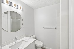 Modern vanity with an integrated sink, polished chrome faucet, round wall mirror, and a contemporary light fixture - 