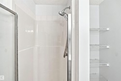 Shower with white tile surround, glass enclosure, and mounted shower head - 