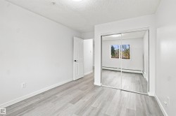 Room featuring wood-finish flooring, a white paneled door with dark hardware, and a mirrored sliding closet door - 
