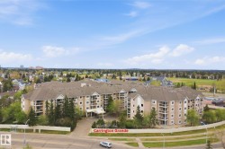Multi-story residential building featuring multiple balconies, a covered entrance, and surrounding mature trees - 