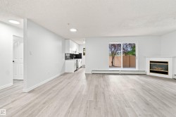 Open-concept living space with wood-finish flooring, a white mantel fireplace, and a sliding glass door - 