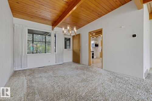 Vaulted wood-paneled ceiling, exposed wood beams, wall-to-wall carpeting, multi-paned window, and a built-in chandelier - 7508 139 Street Nw, Edmonton, AB 