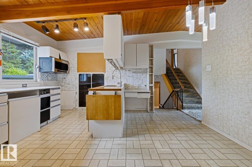 Kitchen featuring a wood-panel ceiling with exposed beams, track lighting, and a modern chandelier - 7508 139 Street Nw, Edmonton, AB 