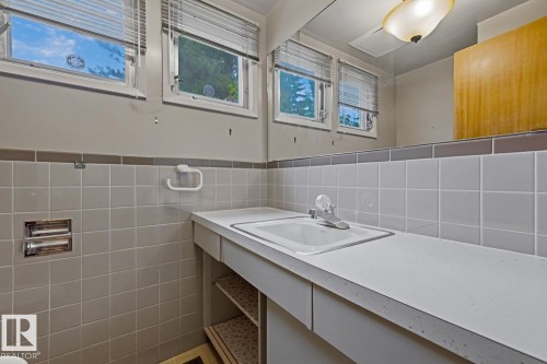 Integrated vanity with a drop-in sink, tiled walls, and two windows with blinds - 7508 139 Street Nw, Edmonton, AB 