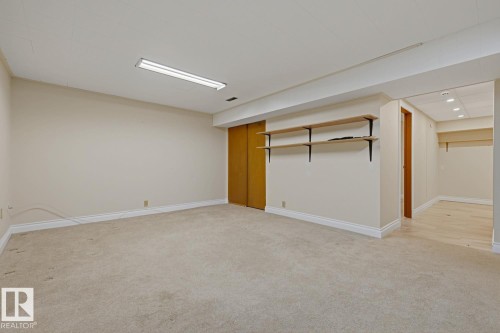 Carpeted floor, wood-finish bi-fold doors, wall-mounted shelving, overhead fluorescent lighting, and recessed ceiling lights - 7508 139 Street Nw, Edmonton, AB 