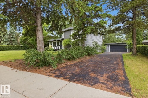 Split-level residence featuring a gray exterior, covered entry, and attached garage with a dark paneled door - 7508 139 Street Nw, Edmonton, AB 