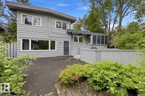 Gray siding exterior with multiple windows, an enclosed porch, and a surrounding deck with a privacy fence - 7508 139 Street Nw, Edmonton, AB 