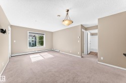 Neutral wall color, carpeted flooring, window with white trim, built-in baseboard heating, and an overhead decorative light fixture - 