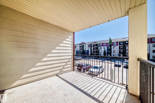 Balcony featuring a textured concrete surface, metal railing, and a horizontal siding exterior - #218 5810 Mullen Pl Nw Nw, Edmonton, AB 