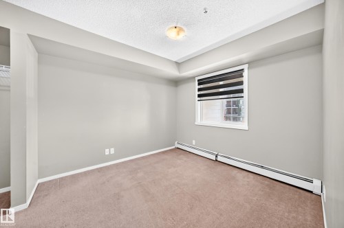 Neutral wall paint with carpet flooring, window with blinds, and baseboard heating - #218 5810 Mullen Pl Nw Nw, Edmonton, AB 