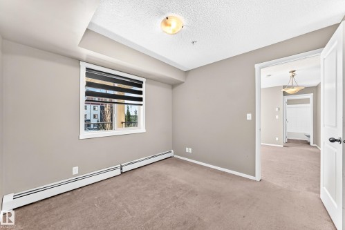 Carpeted room with neutral wall tones and a window with blinds - #218 5810 Mullen Pl Nw Nw, Edmonton, AB 