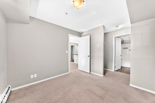 Neutral-toned carpeting, white interior doors, and a ceiling-mounted light fixture - #218 5810 Mullen Pl Nw Nw, Edmonton, AB 