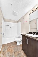 Tile flooring, white subway tile shower surround, shower/tub combination, dark wood-finish vanity, and a white basin sink - 