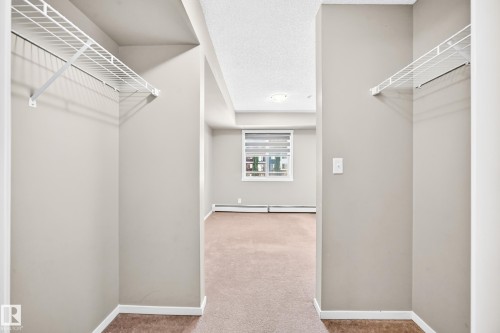 Neutral-toned walls complement the carpeted flooring - #218 5810 Mullen Pl Nw Nw, Edmonton, AB 