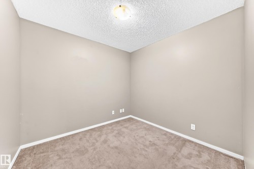 Neutral-toned walls complement the carpeted flooring - #218 5810 Mullen Pl Nw Nw, Edmonton, AB 