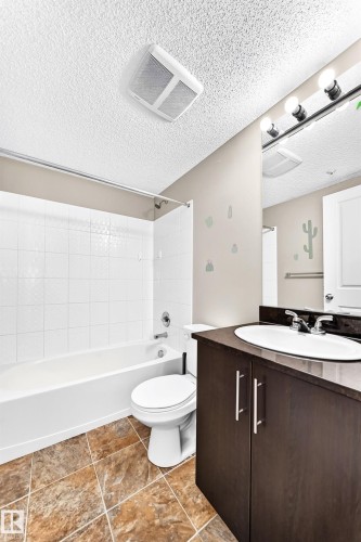 Bathroom featuring a dark wood-finish vanity with a white oval sink, chrome faucet, and overhead bar lighting - #218 5810 Mullen Pl Nw Nw, Edmonton, AB 