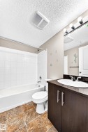 Bathroom featuring a dark wood-finish vanity with a white oval sink, chrome faucet, and overhead bar lighting - 