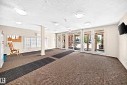 Building entrance with multiple glass-paneled doors, neutral-toned walls, recessed lighting, and textured carpeting - 