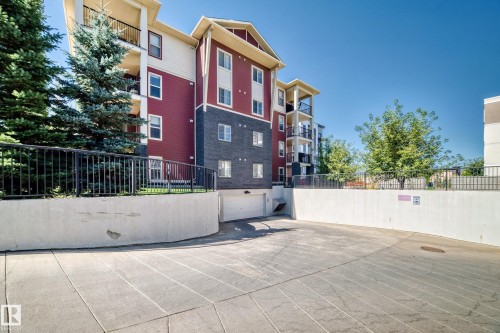 Multi-story building featuring a red and dark gray facade with white trim - #218 5810 Mullen Pl Nw Nw, Edmonton, AB 