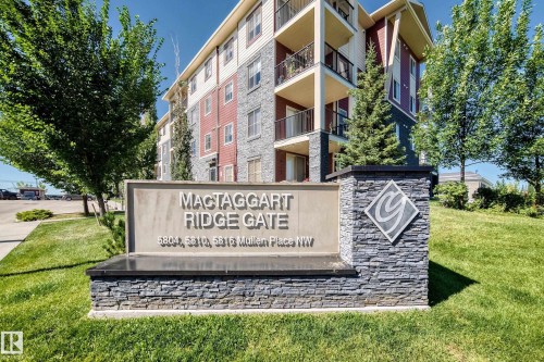 Stone-clad monument sign featuring a detailed emblem and property name - #218 5810 Mullen Pl Nw Nw, Edmonton, AB 