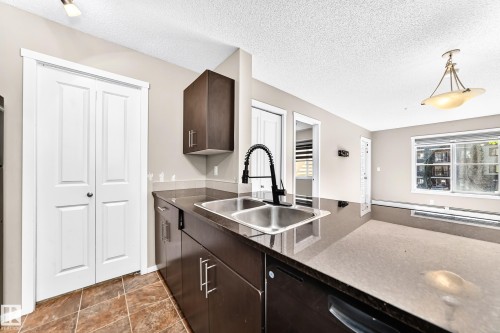 Stainless steel double basin sink with a matte black pull-down faucet - #218 5810 Mullen Pl Nw Nw, Edmonton, AB 