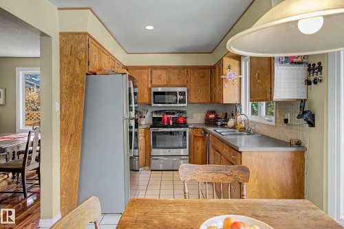 Kitchen featuring wood-finish cabinetry, stainless steel appliances, and tile flooring - 36 Lodgepole Crescent, St. Albert, AB 