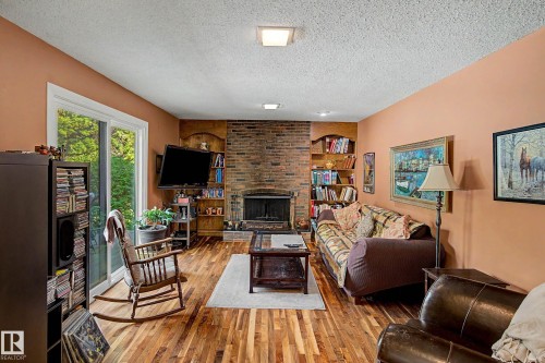 Brick fireplace with built-in shelving, wood-finish flooring, and sliding glass doors - 36 Lodgepole Crescent, St. Albert, AB 
