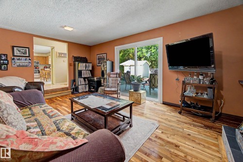 Living space with wood-finish flooring, direct patio access via sliding glass doors, and recessed lighting - 36 Lodgepole Crescent, St. Albert, AB 