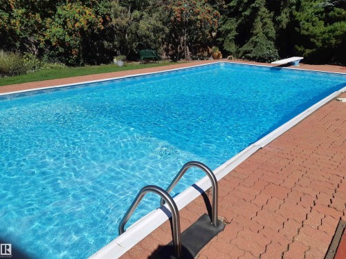This is the pool in 2025   which can be returned to this condition ,   Rectangular swimming pool with clear water, integrated diving boar, and stainless steel grab rails - 36 Lodgepole Crescent, St. Albert, AB 