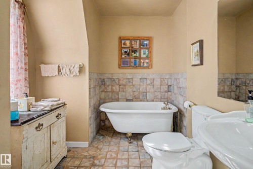 Tile flooring with a freestanding clawfoot tub, partial tile wall surround, and a pedestal sink - 36 Lodgepole Crescent, St. Albert, AB 