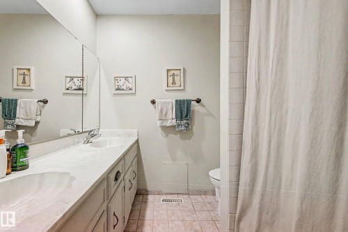 Double vanity with integrated sinks, expansive wall-mounted mirror, and tile flooring - 36 Lodgepole Crescent, St. Albert, AB 