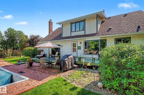 Expansive backyard featuring a red brick patio, green lawn, a covered pool, and mature perimeter trees - 36 Lodgepole Crescent, St. Albert, AB 