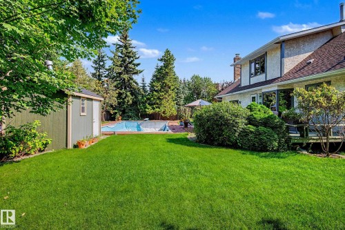 Expansive backyard featuring a green lawn, covered swimming pool, and a storage shed - 36 Lodgepole Crescent, St. Albert, AB 