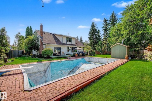 Expansive backyard featuring a large swimming pool, brick patio, and a detached shed - 36 Lodgepole Crescent, St. Albert, AB 