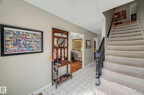 Tiled flooring entry with a carpeted staircase and dark wood-finish banister - 36 Lodgepole Crescent, St. Albert, AB 