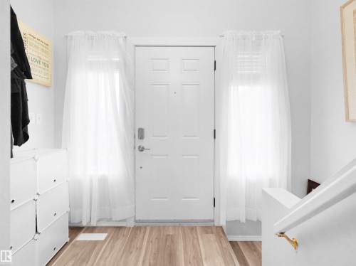 White front door with secure deadbolt and coordinating hardware, flanked by two side-panel windows - 15511 45 Street Nw, Edmonton, AB 