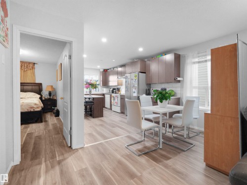 Wood-finish flooring throughout, recessed lighting, and a kitchen with stainless steel appliances, dark wood-finish cabinetry, and white subway tile backsplash - 15511 45 Street Nw, Edmonton, AB 
