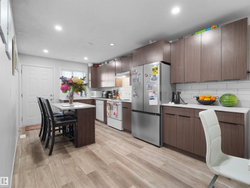 Contemporary kitchen with wood-finish cabinetry, white countertops, subway tile backsplash, and light wood-finish flooring - 15511 45 Street Nw, Edmonton, AB 