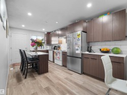 Contemporary kitchen with wood-finish cabinetry, white countertops, subway tile backsplash, and light wood-finish flooring - 