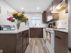 Kitchen with wood-finish flooring, wood-look cabinetry, light countertops, and white subway tile backsplash - 